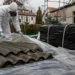 Pracovník v ochranném vybavení připravuje neporušené eternitové desky k odbornému odvozu