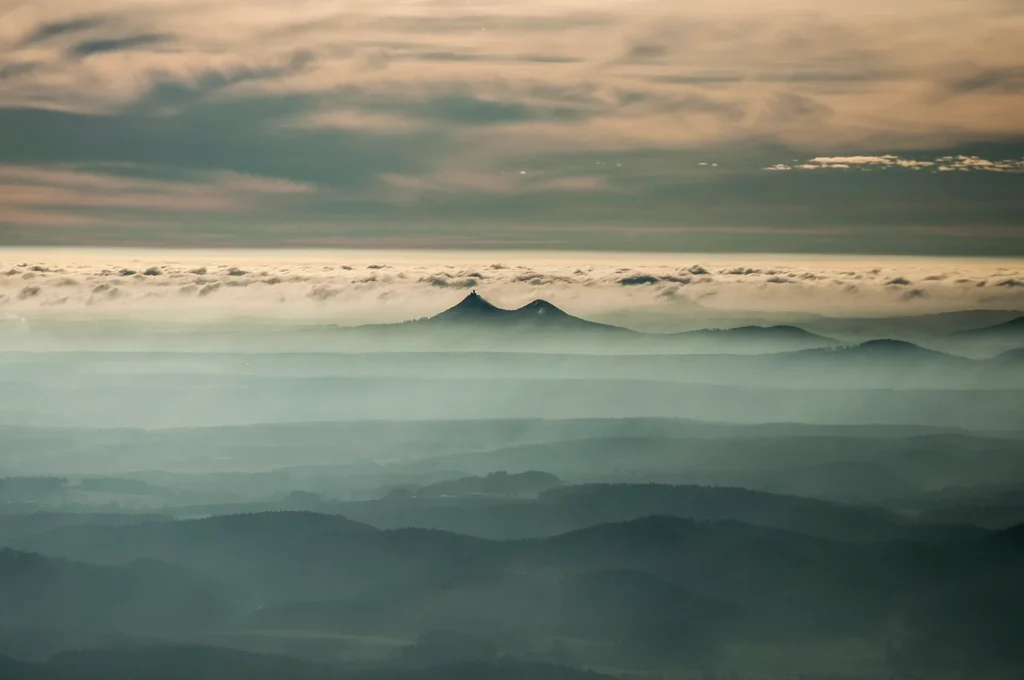 Velký a Malý Bezděz nad mlhavou krajinou, silueta hradu na levém vrcholu; skutečná archivní fotografie