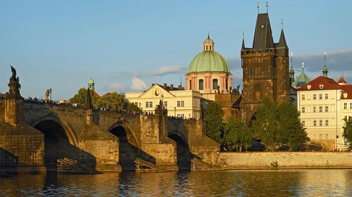 Karlův most se Staroměstskou mosteckou věží a kupolí kostela sv. Františka z Assisi ve večerním světle