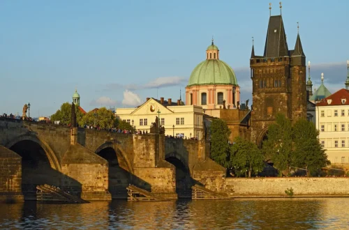 Karlův most se Staroměstskou mosteckou věží a kupolí kostela sv. Františka z Assisi ve večerním světle