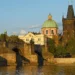 Karlův most se Staroměstskou mosteckou věží a kupolí kostela sv. Františka z Assisi ve večerním světle