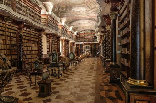 Barokní knihovní sál Klementina s freskami na stropě, galerií a historickými glóby