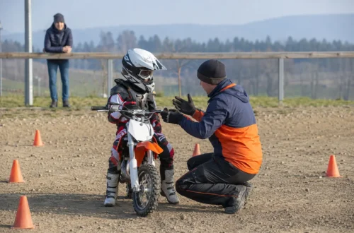 Dítě v kompletní výbavě poslouchá trenéra před první motokrosovou lekcí