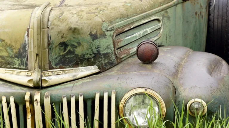 Zrezivělé staré auto zarostlé trávou