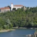 Hrad Bítov na zalesněném skalním ostrohu nad hladinou Vranovské přehrady
