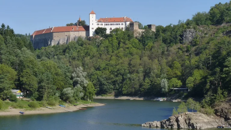 Hrad Bítov na zalesněném skalním ostrohu nad hladinou Vranovské přehrady