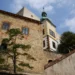 Hrad Buchlov, kamenný palác a hodinová věž se zelenou bání nad nádvořím, v popředí borovice