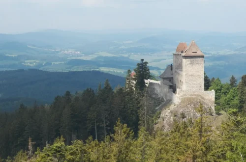 Gotický hrad Kašperk se dvěma věžemi na zalesněném kopci nad Šumavou, pohled z Pustého hrádku