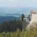 Gotický hrad Kašperk se dvěma věžemi na zalesněném kopci nad Šumavou, pohled z Pustého hrádku