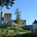Zřícenina hradu Landštejn s velkou románskou věží, hradbami a bílou vstupní budovou ve večerním slunci