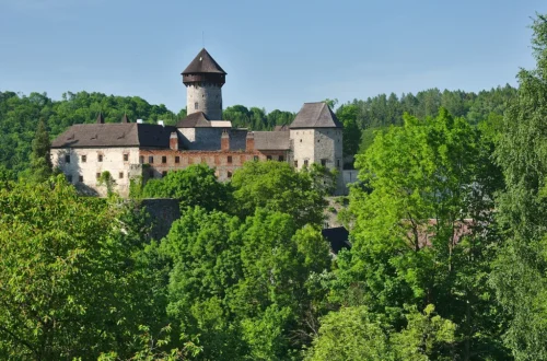 Hrad Sovinec s válcovou hlavní věží a paláci nad zeleným lesem v Nízkém Jeseníku