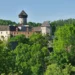 Hrad Sovinec s válcovou hlavní věží a paláci nad zeleným lesem v Nízkém Jeseníku