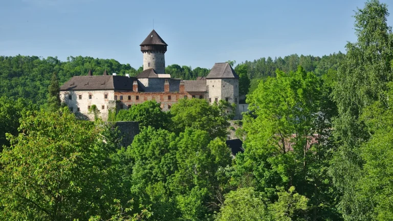 Hrad Sovinec s válcovou hlavní věží a paláci nad zeleným lesem v Nízkém Jeseníku