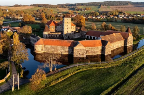 Vodní hrad Švihov z výšky v podzimních barvách, s věží, baštami a hradbami obklopenými vodním příkopem