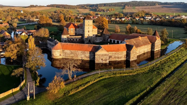 Vodní hrad Švihov z výšky v podzimních barvách, s věží, baštami a hradbami obklopenými vodním příkopem