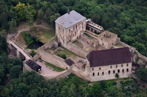 Hrad Točník z výšky s Královským a Purkrabským palácem na zalesněném hřebeni nad Žebrákem