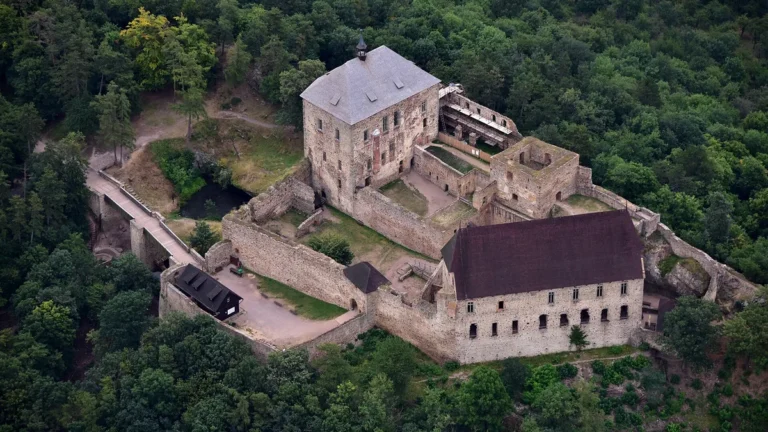 Hrad Točník z výšky s Královským a Purkrabským palácem na zalesněném hřebeni nad Žebrákem