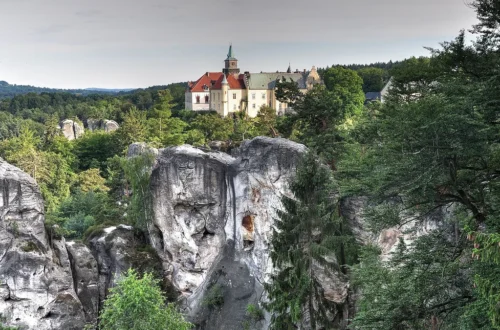 Zámek Hrubá Skála nad pískovcovými věžemi Hruboskalska, v pozadí vlevo zřícenina Trosky