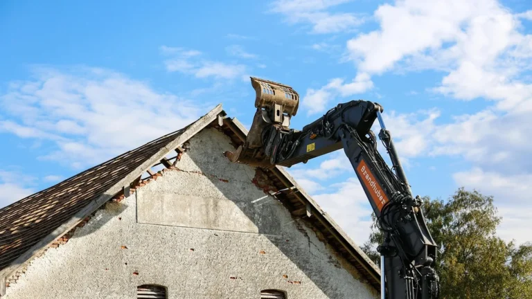 Bagr bourá střechu starého domu