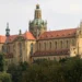Kostel Nanebevzetí Panny Marie v klášteře Kladruby s kopulí a zlacenou korunou nad korunami stromů