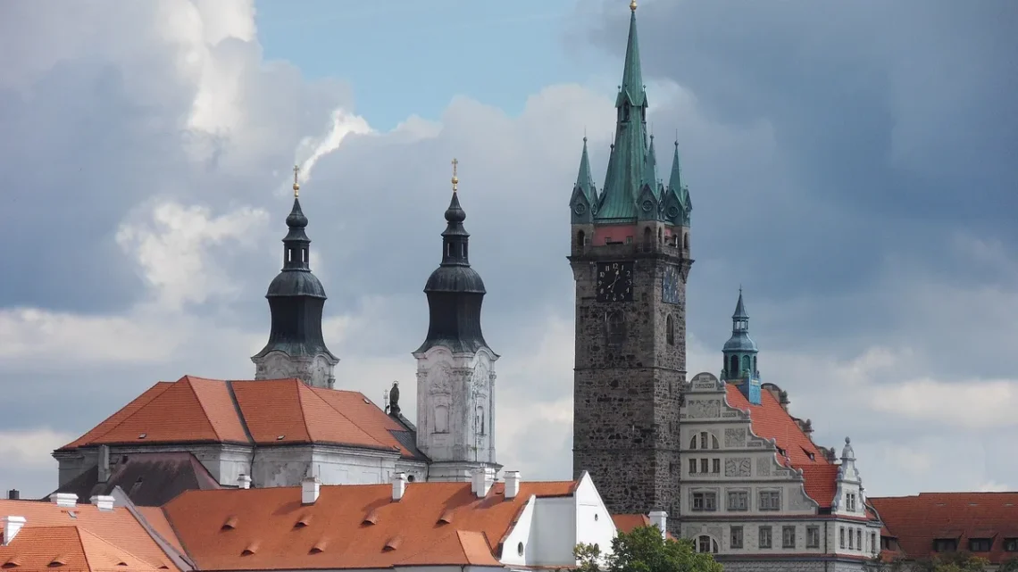 Černá věž a dvě věže jezuitského kostela nad střechami Klatov