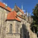 Kamenná boční stěna chrámu sv. Bartoloměje v Kolíně s červenou střechou kaple a gotickými věžičkami chóru