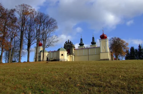 Barokní poutní areál Hora Matky Boží nad Králíky s věžemi kostela a ambity za podzimní alejí
