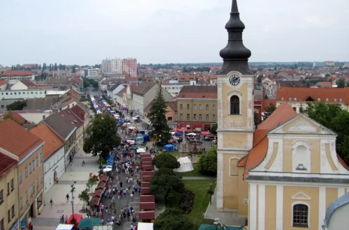 Pohled z radniční věže na kostel sv. Vavřince s hodinovou věží a na Masarykovo náměstí v Hodoníně plné stánků a lidí