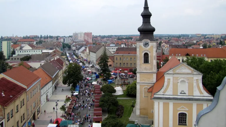 Pohled z radniční věže na kostel sv. Vavřince s hodinovou věží a na Masarykovo náměstí v Hodoníně plné stánků a lidí