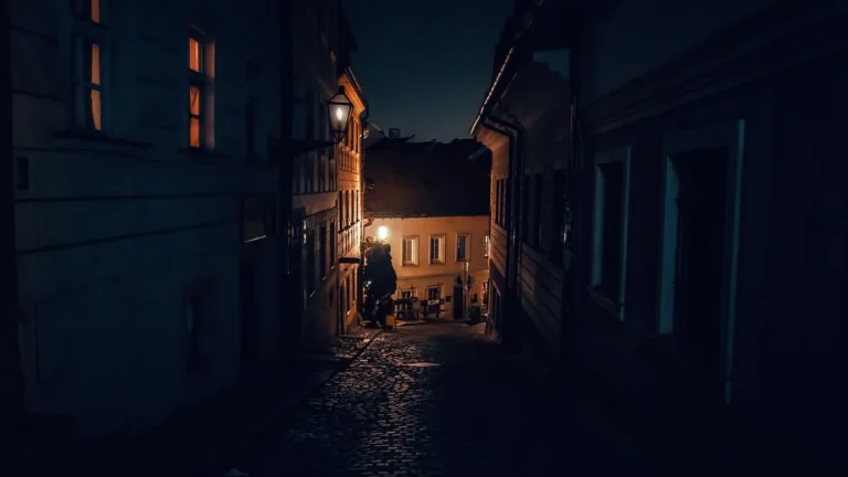 Úzká ulička starého města v noci se svítícími okny
