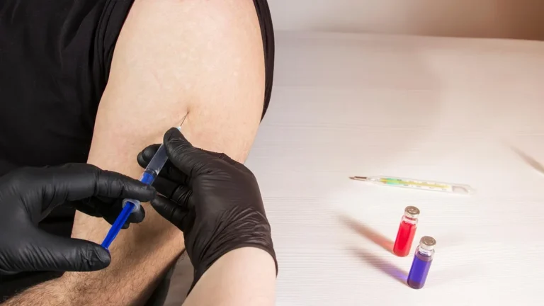 Zdravotník očkuje do paže, vedle jsou ampulky