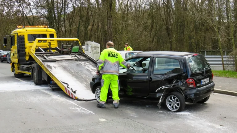 Odtahový vůz nakládá poškozené auto na ulici