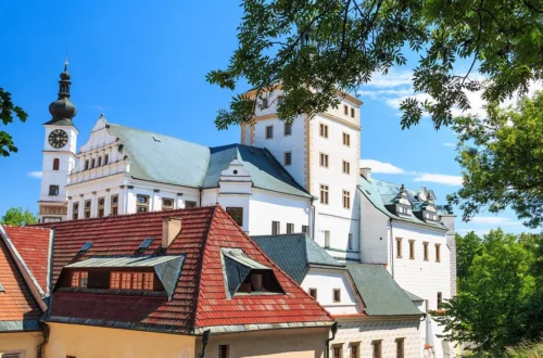 Zámek Pardubice s hodinovou věží a renesančními štíty nad střechami domů v letním dni