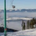Zasněžená sjezdovka a sedačková lanovka v ski areálu Ramzová s výhledem na hřebeny Jeseníků nad inverzí