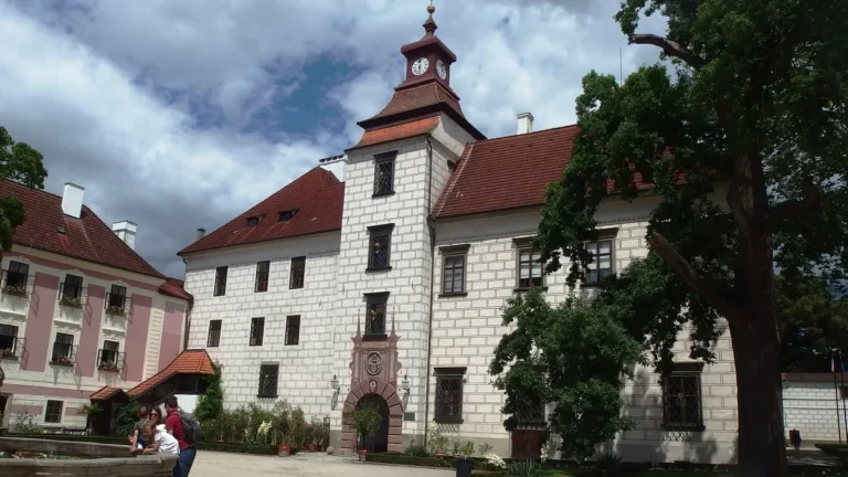 Nádvoří renesančního zámku Třeboň s hodinovou věží, kamennou kašnou a vzrostlým stromem
