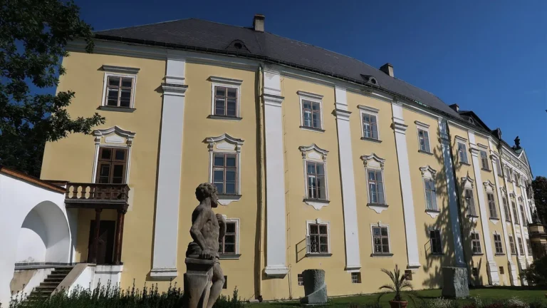 Barokní průčelí zámku Bruntál se sochou Vulkána v zámecké zahradě