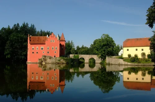 Červený zámek Červená Lhota na skále v rybníce s kamenným mostem a odrazem ve vodě