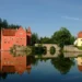 Červený zámek Červená Lhota na skále v rybníce s kamenným mostem a odrazem ve vodě