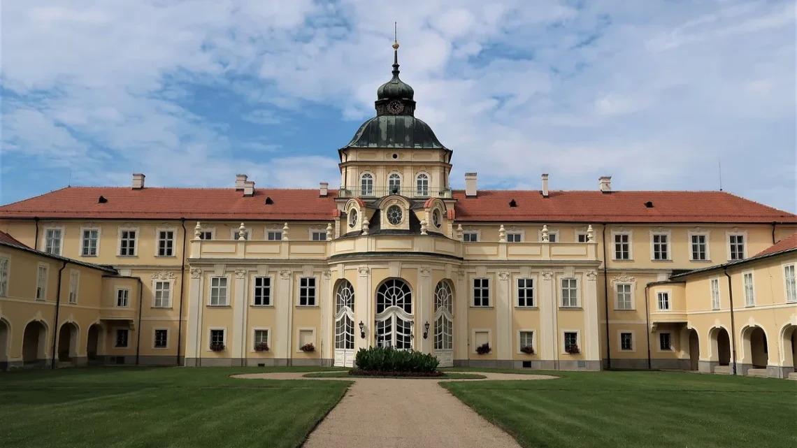 Zahradní průčelí nového zámku v Hořovicích s věží s hodinami a trávníkem před vchodem
