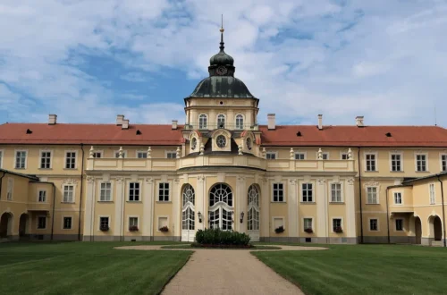 Zahradní průčelí nového zámku v Hořovicích s věží s hodinami a trávníkem před vchodem