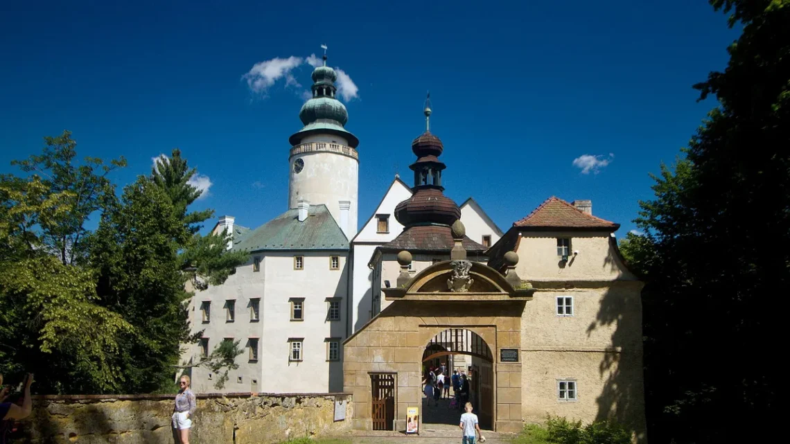 Barokní zámek Lemberk s bílou věží a kamennou vstupní branou za slunečného letního dne
