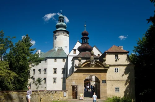 Barokní zámek Lemberk s bílou věží a kamennou vstupní branou za slunečného letního dne