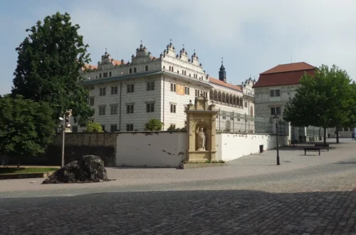 Renesanční zámek Litomyšl se sgrafitovou fasádou a arkádami za ohradní zdí s barokní sochou