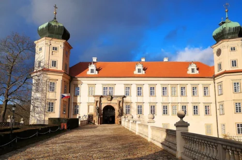 Vstupní průčelí zámku Mníšek pod Brdy se dvěma věžemi a dlážděným mostem