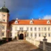 Vstupní průčelí zámku Mníšek pod Brdy se dvěma věžemi a dlážděným mostem