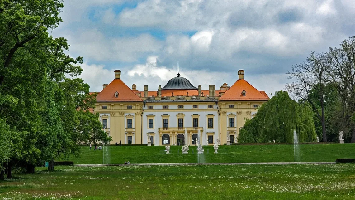 Zahradní průčelí barokního zámku Slavkov u Brna s fontánami a sochami v zámeckém parku