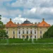 Zahradní průčelí barokního zámku Slavkov u Brna s fontánami a sochami v zámeckém parku