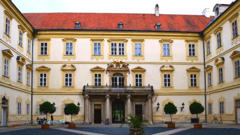 Vnitřní nádvoří zámku Valtice s balkonem nad vstupem a stromky v kbelících