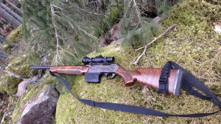 Lovecká puška s optikou ležící na mechu