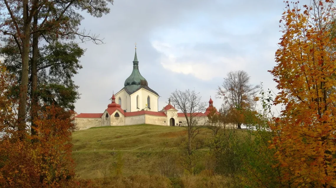 Poutní kostel svatého Jana Nepomuckého na Zelené hoře ve Žďáru nad Sázavou na podzim, s ambitem a stromy v popředí